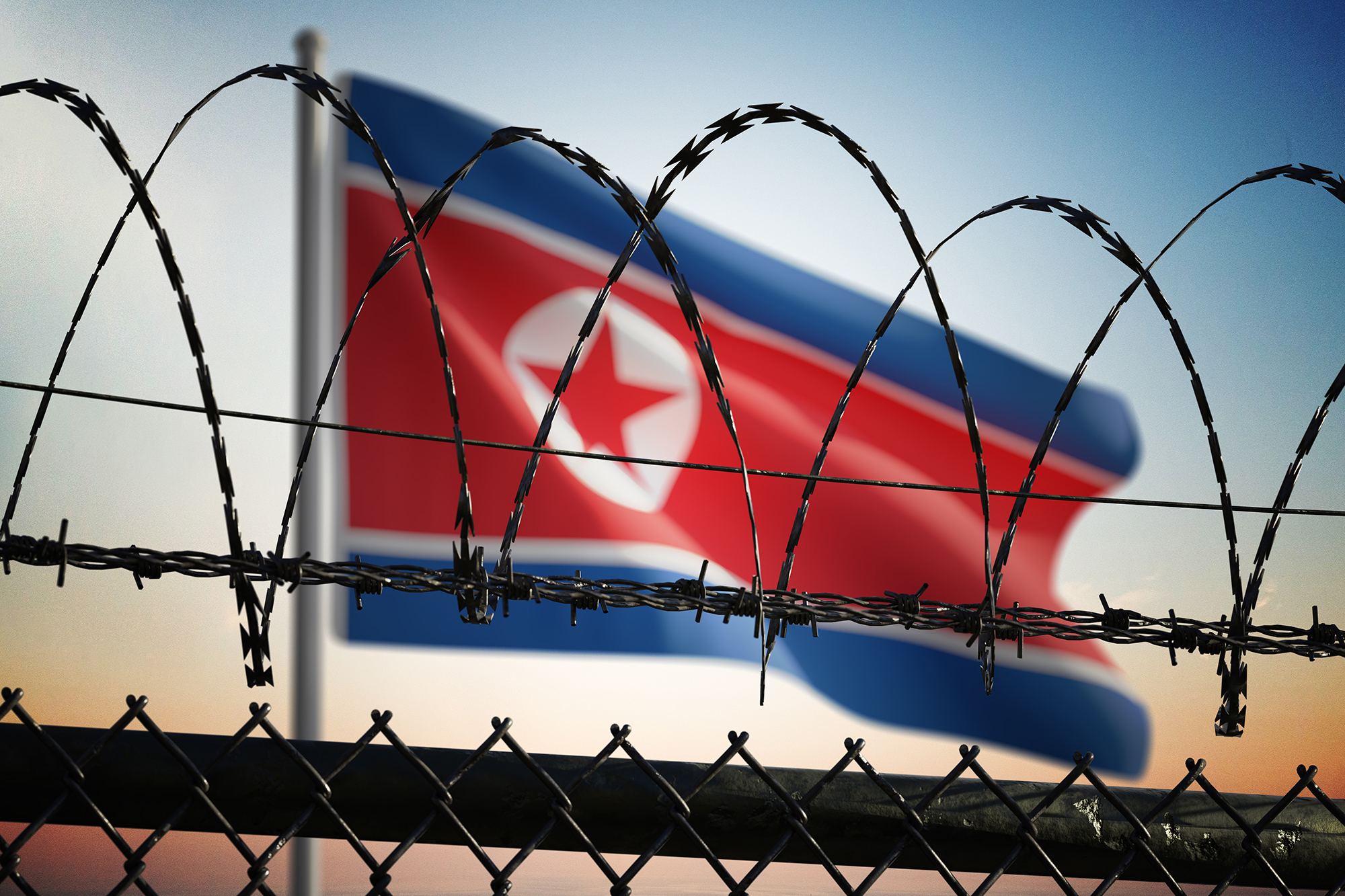 Flag of North Korea behind barbed wire fence. Freedom concept. 3D rendered illustration.